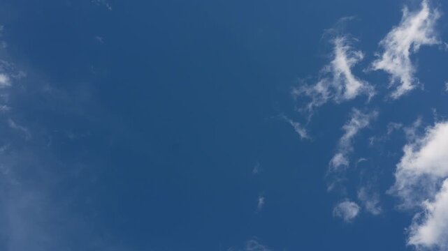 Time lapse of wispy white clouds moving across clear blue sky