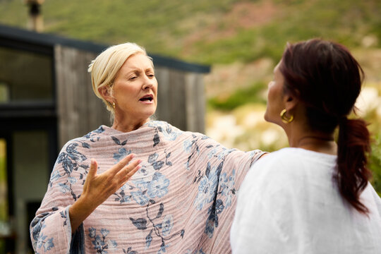 Two Women Talk Outdoors in a Garden Setting