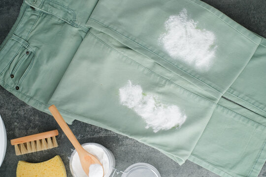 Green jeans sprinkled baking soda powder. Natural cleaning alternatives products for removing stains from clothes. Concept alternative and eco-friendly cleaning products. top view
