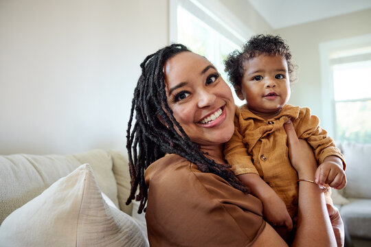 Mother Holds Baby While Smiling in Living Room