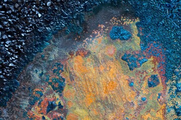 Fototapeta premium Abstract mineral texture with black crystals and colorful oxidation patterns, artistic geological background, macro surface detail