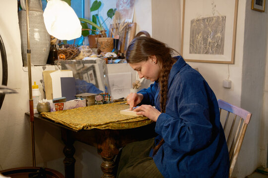 Female artist in her studio creating woodcut print