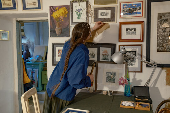 A female artist hangs paintings on the wall