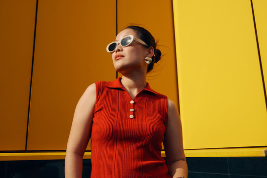 Portrait of a woman in sunglasses against a yellow wall