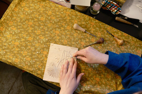 the hands of an artist creating a woodcut.