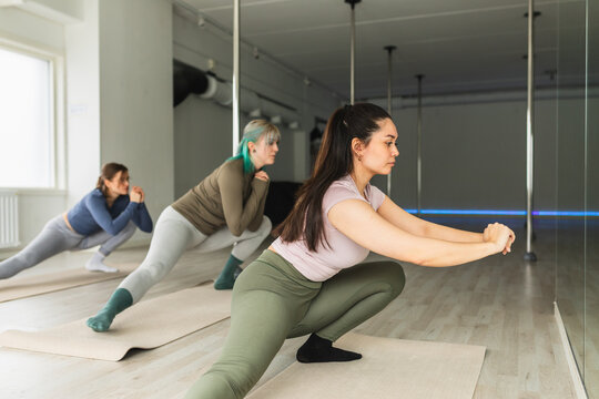 Athletic women practicing side lunges in a row