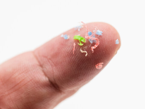 Trozos de micropl&aacute;sticos sobre un dedo de la mano