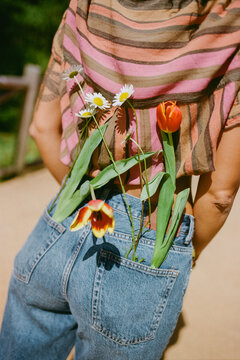 Woman in jeans with flowers in back pocket on a sunny day