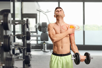 Fototapeta premium Young man suffering from shoulder pain and exercising with weights