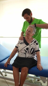 Professional male physiotherapist giving a neck massage to a senior woman in a nursing home. Physical therapy and rehabilitation concept
