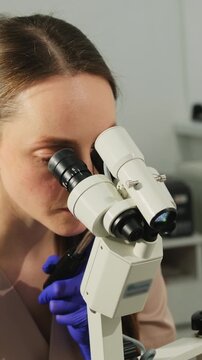 Gynecologist examines cervical area through colposcope during Pap test check. Specialist adjusts optics carefully studying tissue details
