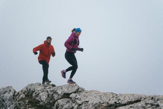 Trail running couple man and woman running on a mountain path