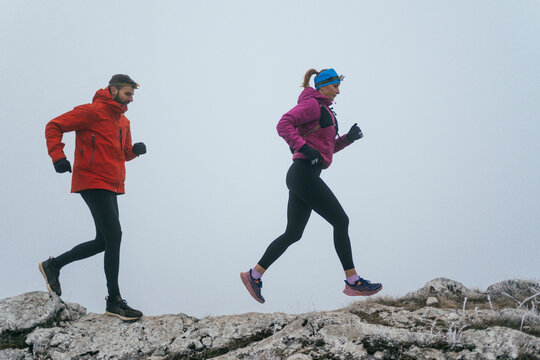 Trail running couple man and woman running on a mountain path