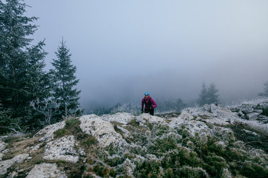 Female Trail Runner in Motion.Back view of female trail runner in pink jacket and black leggings running uphill.