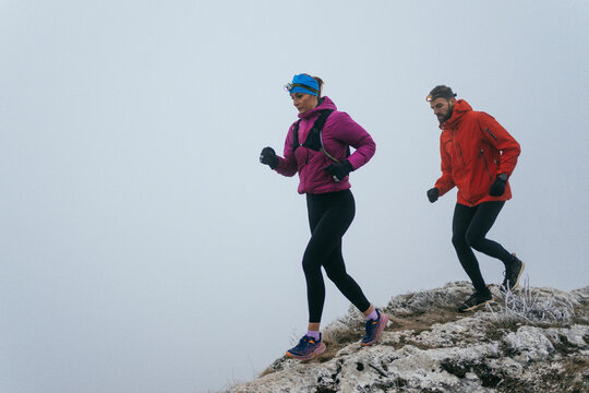 Trail running couple man and woman running on a mountain path