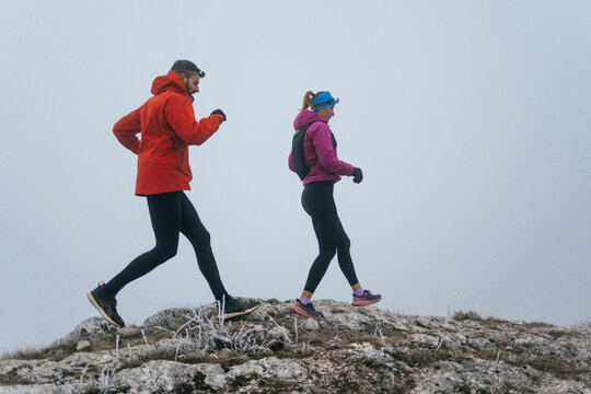 Trail running couple man and woman running on a mountain path
