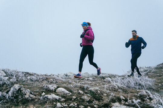 Trail running couple man and woman running on a mountain path