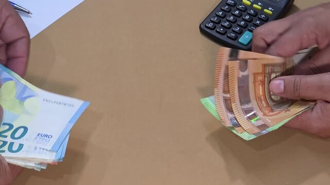 Man hands flipping and handing euro banknotes to a woman, close up view