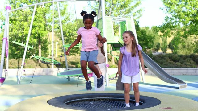 Little girls jumping together on playground trampoline