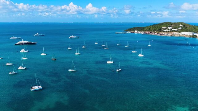 Aerial view of numerous luxury yachts anchored in the turquoise waters of Anse Marcel. This scenic bay is located on the French side of Saint Martin island in the Caribbean Sea. 