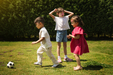 Fototapeta premium Playful Children with Painted Faces Running for Ball