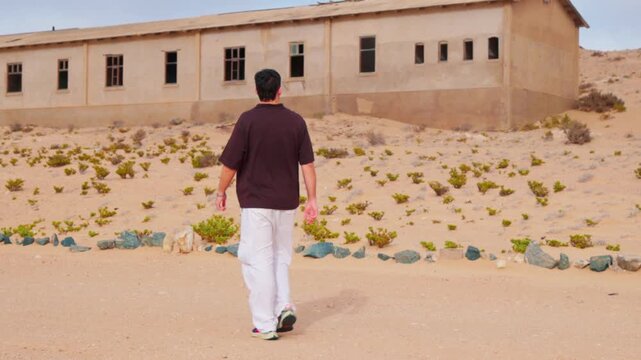 Male tourist walking through the abandoned ghost town of Kolmanskop