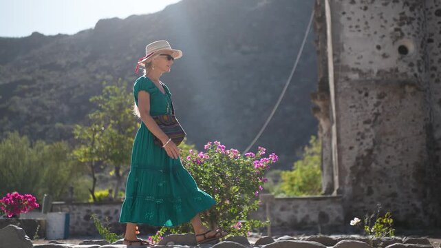 Mature woman smiles and strolls through the garden of San Javier Mission at sunrise in Baja California Sur, Mexico near Loreto