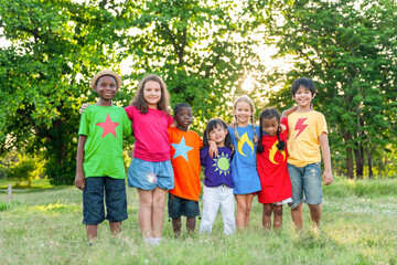 Obraz premium Diverse group of children in colorful shirts, smiling outdoors.