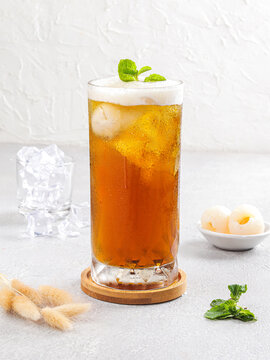 Refreshing Golden Amber Iced Tea with Ice Cubes and Fresh Mint Leaves in a Clear Glass on Minimalist White Background, Summer Beverage Concept