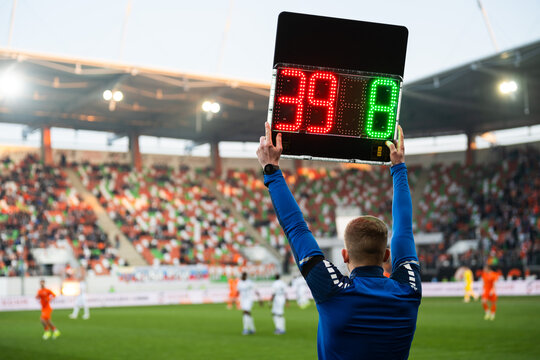 Rear view of a fourth official holding an electronic substitution board showing numbers 39 and 8 at a football stadium.