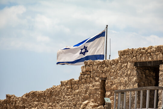 Israeli flag flies proudly over a ruins of Masada fortress in southern Israel near Arad