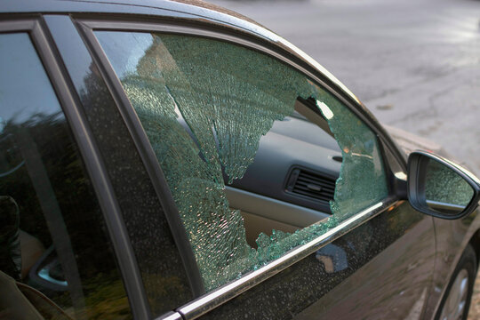 Broken side window of parked car. Vehicle vandalism and insurance claim concept.