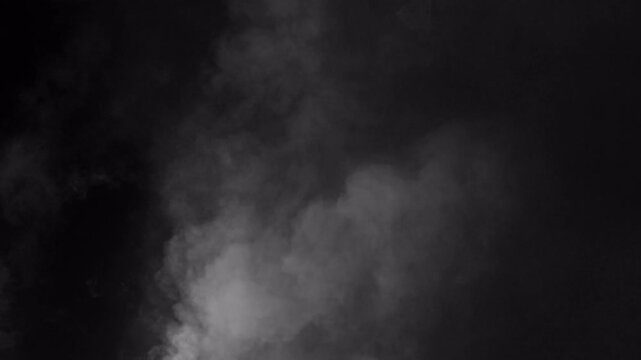 Abstract white smoke or fog rising on black background.
