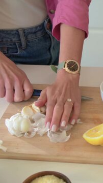 Vertical video: Sparking lemon pink cook and pal making meal on counter using mortar peeling garlic