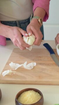 Vertical video: Pouring oil, coral-top woman mashing herbs in home with mortar, lemon, making sauce