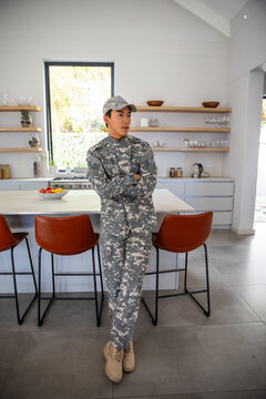 Digital camouflage uniform with tactical boots is leaning against kitchen island with bowl of fruit