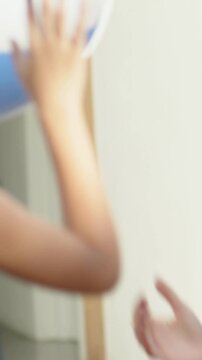 Vertical video: Catching curly child in navy dress taking ball at doorway as ball dropping, playing