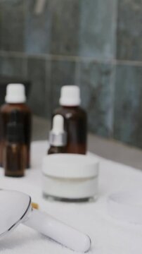 Vertical video: Panning cam zooming on cream jar, amber bottles and tool at sink, showing tiles