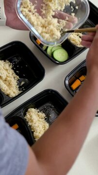 Vertical video: Lifting glass pan, arms adding grain to black trays at home for meals, with watch