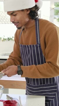Vertical video: Holding sifter man in Santa hat and apron making holiday cake in kitchen with flour