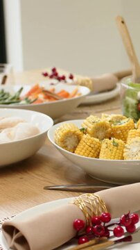 Vertical video: Panning camera presenting corn bowl, beige napkin, gold ring, berry at home table