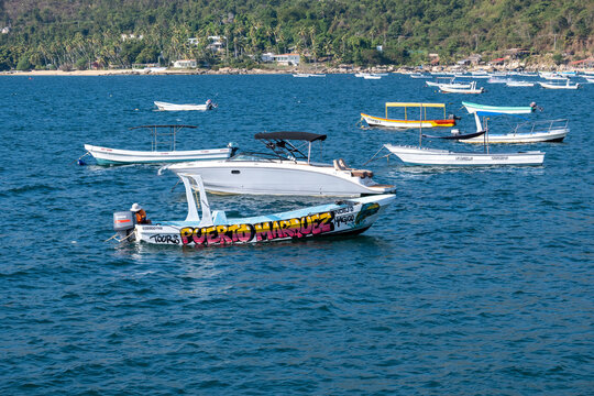 Acapulco, Mexico - January 11 2026: Numerous boats and vessels are moored in the blue waters of Puerto Marquez, Acapulco, with green hills and a bright sky.