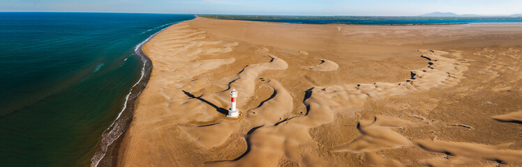 Aerial view of Fangar Lighthouse surrounded by coastal sand dunes and Mediterranean shoreline in the Ebro Delta © StockMediaSeller
