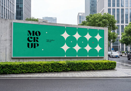 Eye-level perspective view of a massive horizontal street billboard mockup mounted on a concrete wall next to a city road with modern skyscrapers in the background