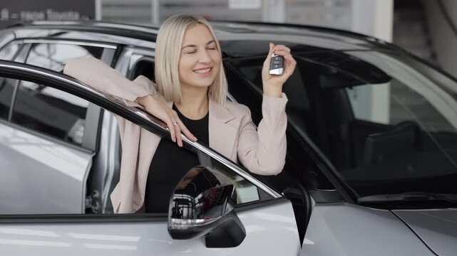 Happy business woman showing car key in dealership
