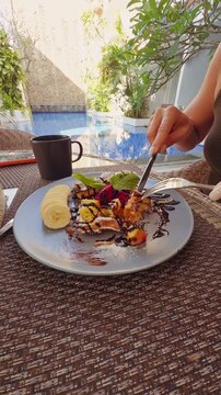 Woman Eating Sweet Pancakes With Fresh Fruit During Poolside Breakfast at Tropical Resort, Relaxed Vacation And Leisure Lifestyle