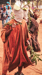 Fototapeta premium Traditional masked dancers perform during a cultural ceremony in the Babungo Kingdom of northwestern Cameroon. Wearing distinctive costumes, face coverings, and ankle rattles