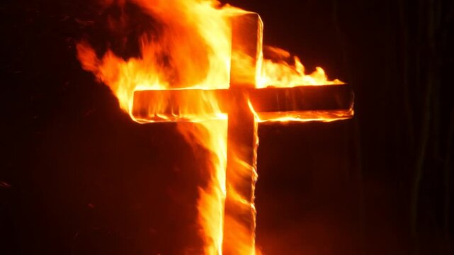Slow motion close up of burning wooden cross engulfed in flames and sparks in dark forest at night