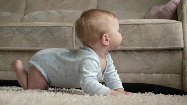 Young child crawls on carpet. Charmingly curious baby moves across comfortable indoor carpet environment. Playful infant investigates warm and inviting area inside house with careful movements