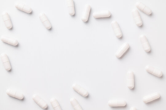 White capsules scattered over a white background